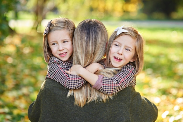 Two little girls embracing their mom