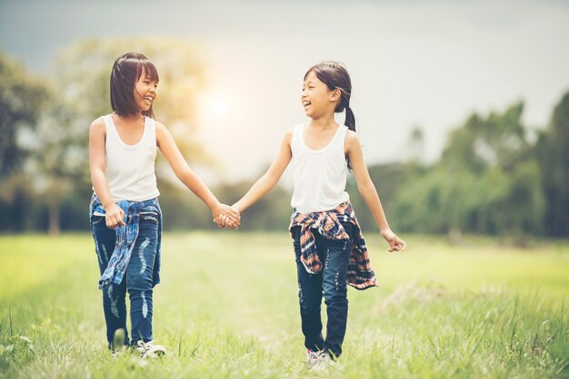 Two little girls hand holding together having fun in the park