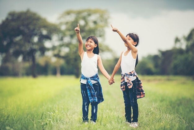 2つの小さな女の子が一緒に公園で楽しいを持って手を