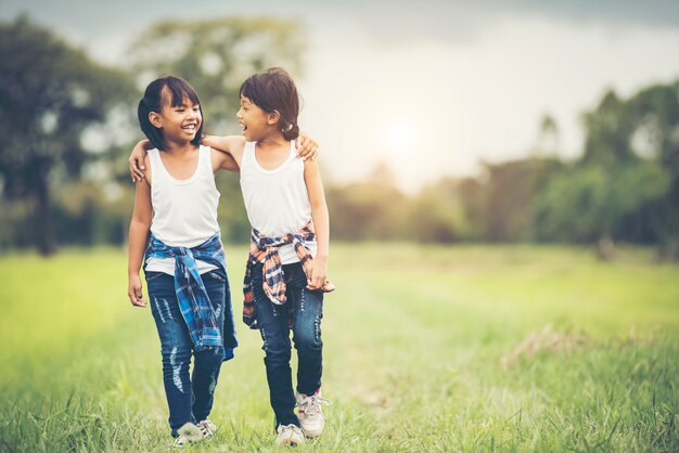 2つの小さな女の子が一緒に公園で楽しいを持って手を