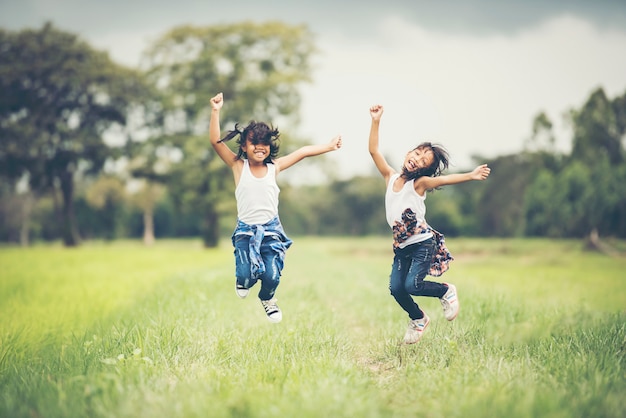 Two little girls happy jump in the nature park