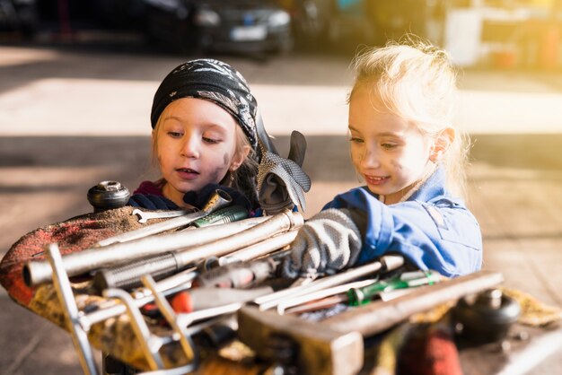 Two little girls in overalls choosing tools 