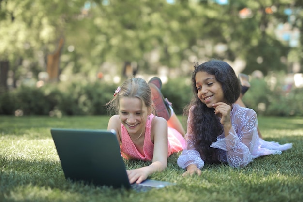 two little girls use a computer in a park