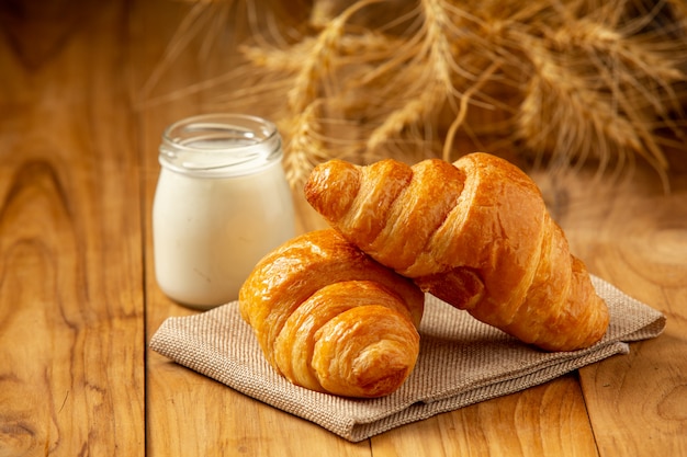 Free photo two loaves of bread and milk put in a glass on the old wooden floor.