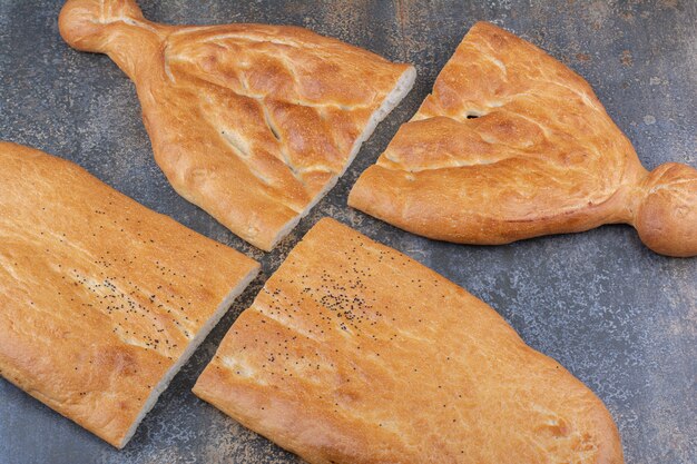 Две буханки хлеба тандури, разрезанные пополам на мраморной поверхности