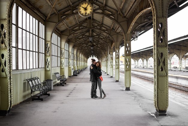 Двое влюбленных обнимаются и целуются на вокзале