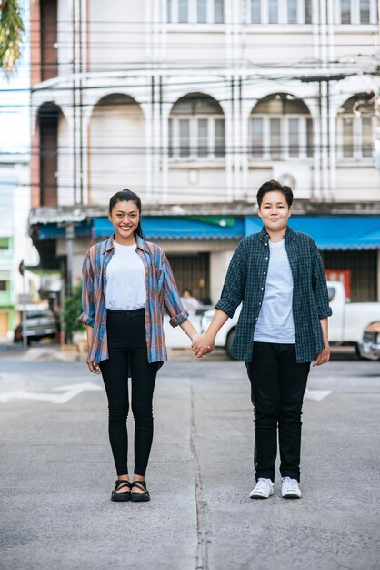 Two loving women standing and holding hands on the street.