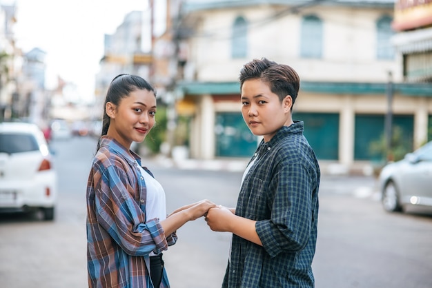 通りに立って手を繋いでいる2人の愛情のある女性。