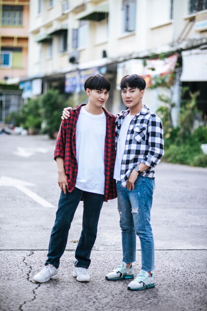 Two loving young men in shirts and standing on the street.