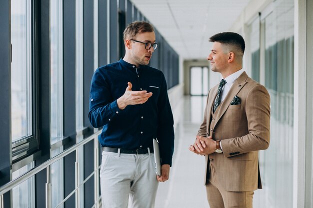 Two male colleagues at the office,standing with laptop