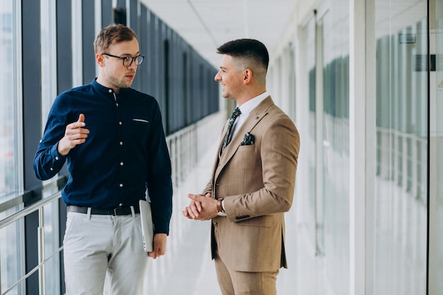 Two male colleagues at the office,standing with laptop