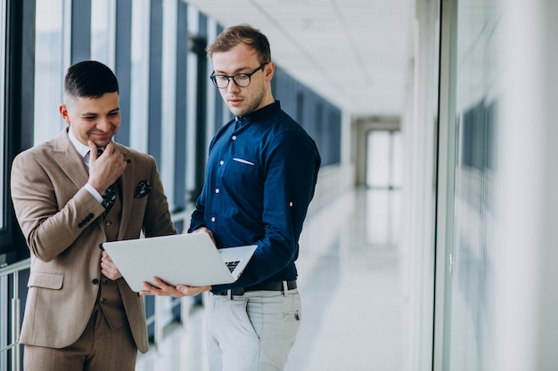 Two male colleagues at the office,standing with laptop