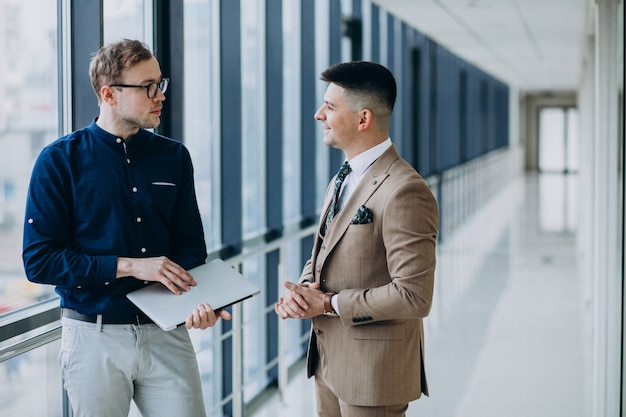 Two male colleagues at the office,standing with laptop