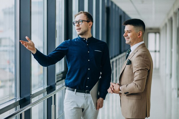 Two male colleagues at the office,standing with laptop