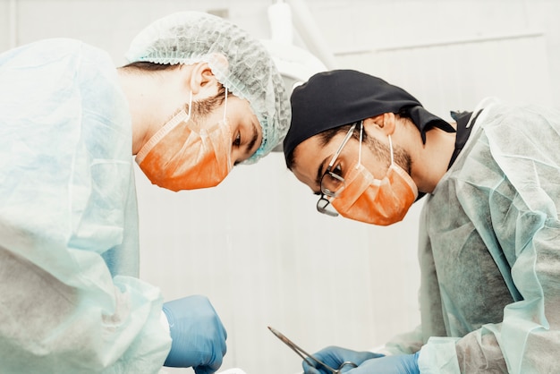 Two male dentists perform an operation on a patient. surgery in dentistry. professional uniform and equipment of a dentist. healthcare equipping a doctorã¢ââs workplace. dentistry