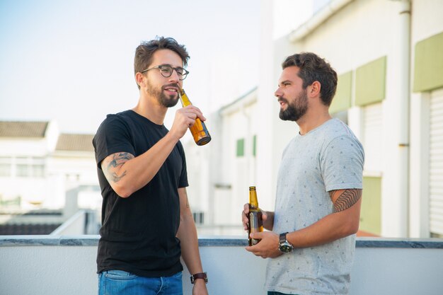 Two male friends enjoying party, chatting, drinking beer