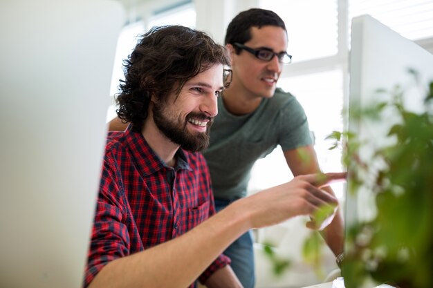 Two male graphic designers interacting over computer