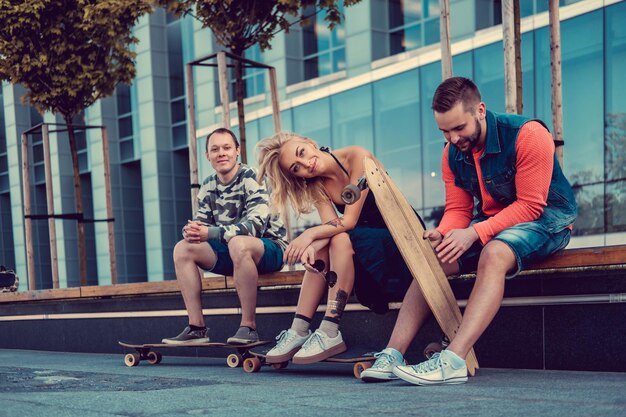 Two males and one female with longboards posing on the street in urban style.