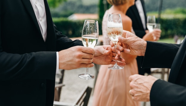 Two man clang glasses with champagne standing in the hall during