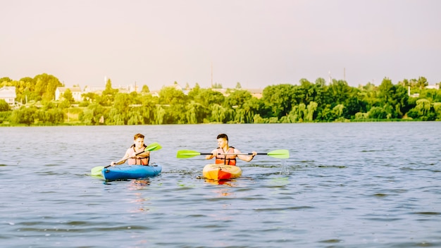 Foto gratuita due uomini che rema il kayak sul lago