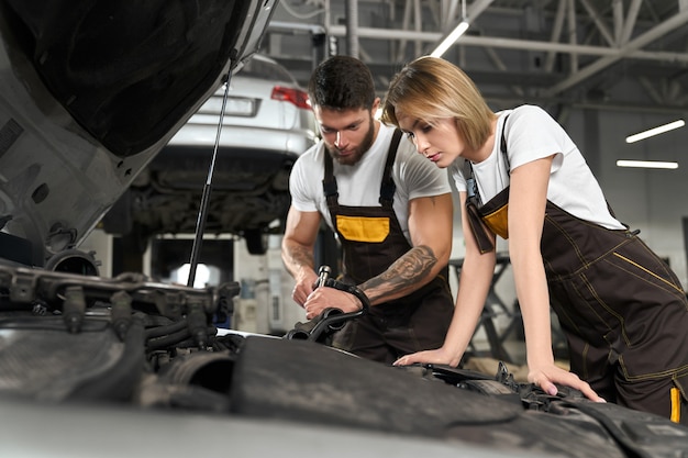 Two mechanics repairing car in professional autoservice.