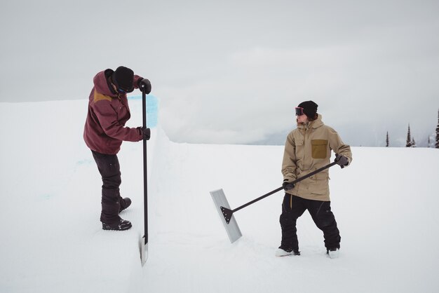 Двое мужчин убирают снег на горнолыжном курорте