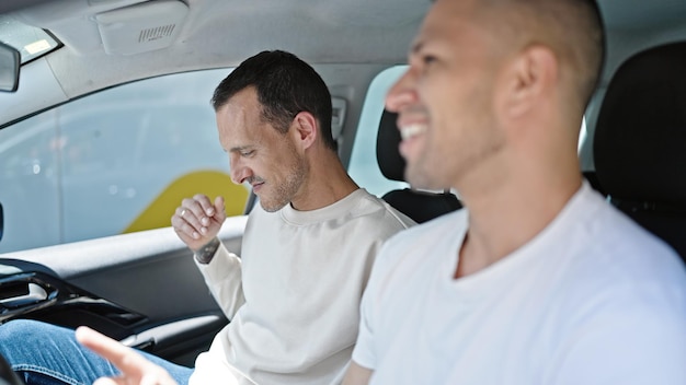 Two men couple sitting on car dancing at street