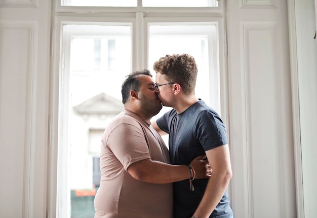 二人の男が家の中で抱き合ってキスします