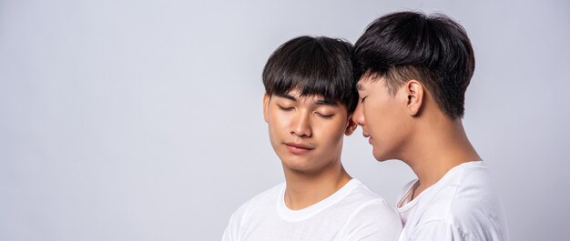 Two men in love wearing white t-shirts looked at each other's faces.