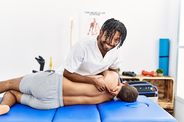 Free photo two men physiptherapist and patient having rehab session massaging back at clinic