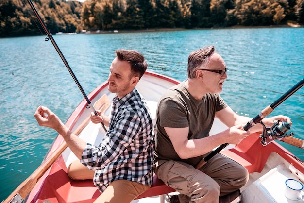 Двое мужчин сидят и ловят рыбу в каноэ