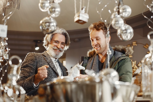 Two men in a store. Grandfather with adult grandson. People choose Christmas gifts.