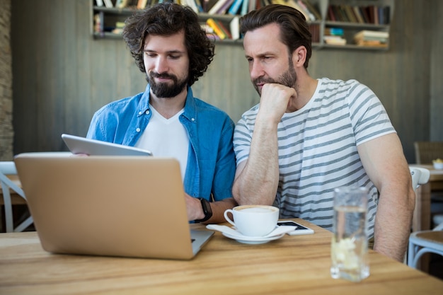 Two men using digital tablet and laptop