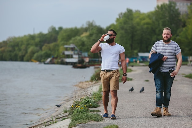 Free photo two men walk and drink coffee