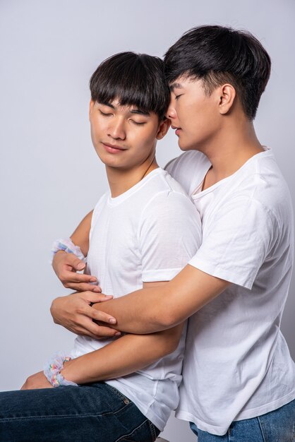 Two men who love each other hug from behind another.