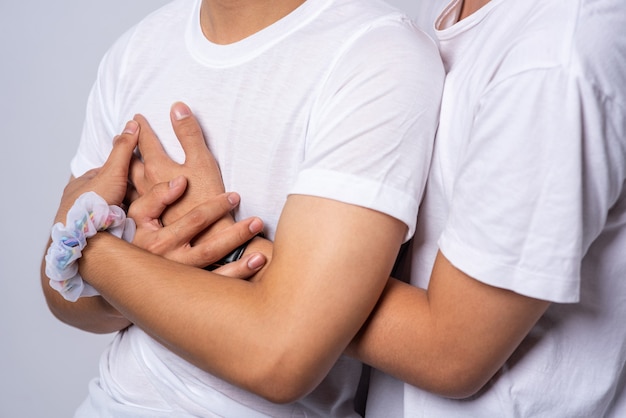 Two men who love each other hug from behind another.