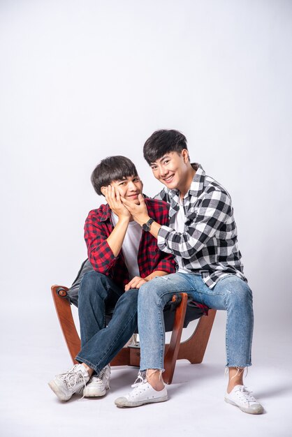 Two men who love each other hug and sit on a chair.