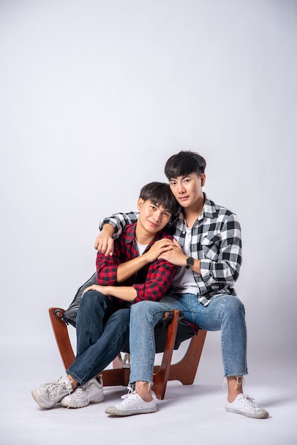 Two men who love each other hug and sit on a chair.