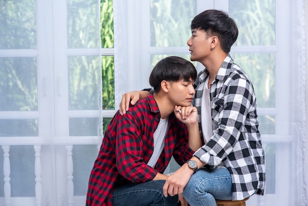 Two men who love each other hug and sit on a chair.