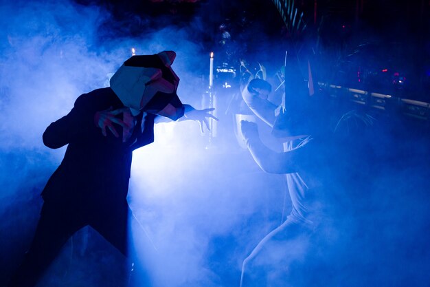 Two men with animal masks posing at the party in the club