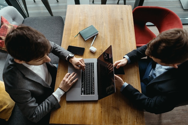 Two men working at laptop during a meeting in a cafe