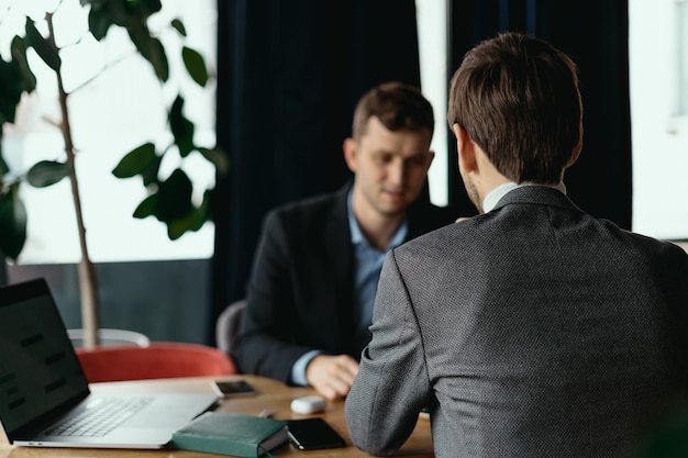 Two men working at laptop during a meeting in a cafe