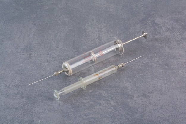 Free photo two metal syringes on marble surface.