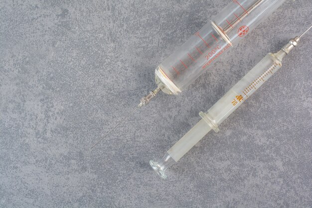 Two metal syringes on marble surface.