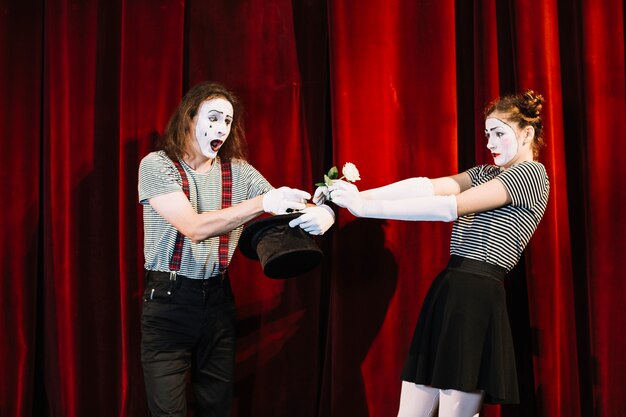 Two mime artist performing on stage in front of red curtain
