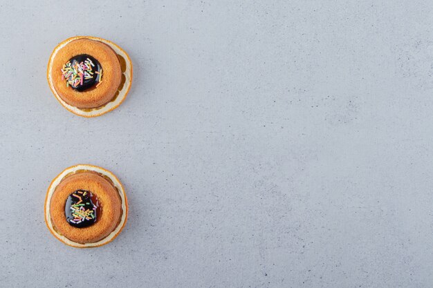 Two mini cakes with jelly placed on top of slice of orange. High quality photo