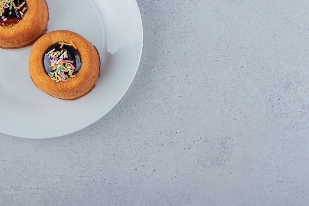 Two mini cakes with jelly placed on white plate. High quality photo