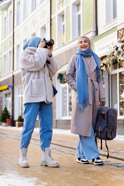 Two muslim female friends taking photos of the buildings while traveling