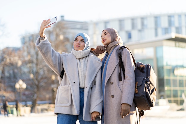 도시를 여행하는 동안 셀카를 찍는 두 명의 이슬람 여성 친구