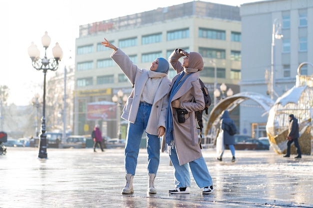 Free photo two muslim female friends walking around the city while traveling